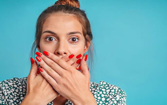 woman covering her mouth with her hands to stop lying