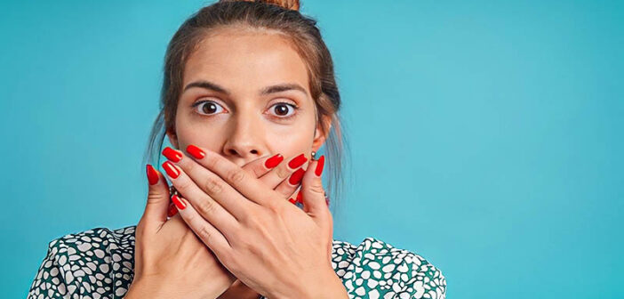 woman covering her mouth with her hands to stop lying