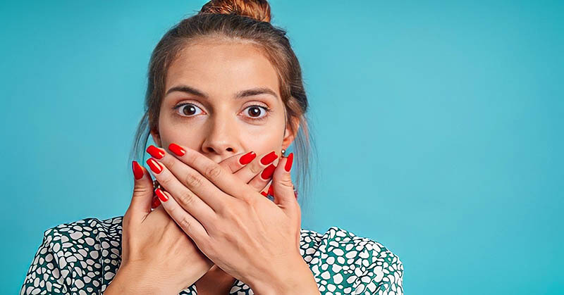 woman covering her mouth with her hands to stop lying