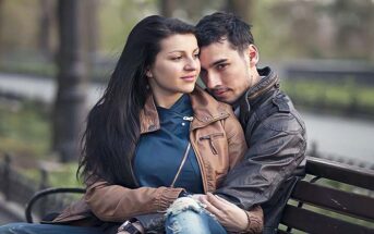 a young couple sitting on a park bench