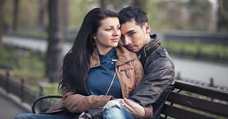 a young couple sitting on a park bench