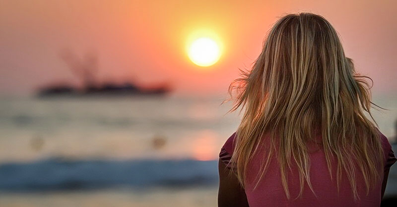 young woman facing sunset - illustrating finding inner peace