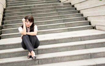 anxious young businesswoman sitting on some steps illustrating a fear of success