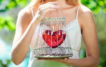 woman holding her heart in a cage illustrating needing to open up to love