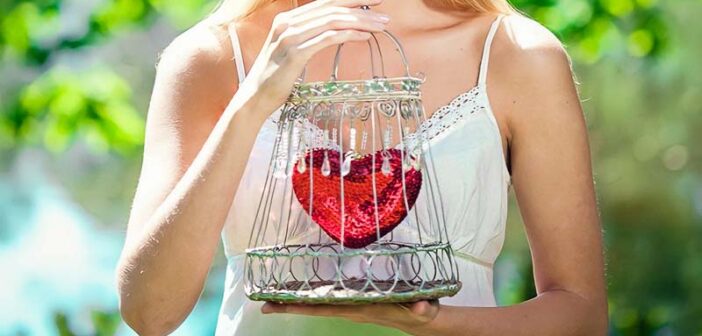 woman holding her heart in a cage illustrating needing to open up to love