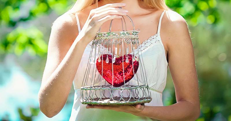 woman holding her heart in a cage illustrating needing to open up to love