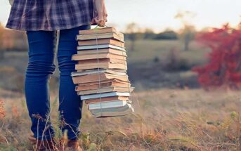 woman with stack of books in nature - illustrating hobbies for introverts