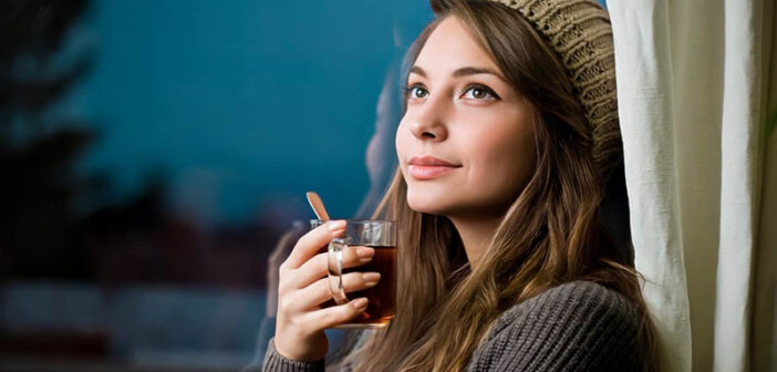 smiling thoughtful woman holding a hot drink - illustrating being the best version of yourself