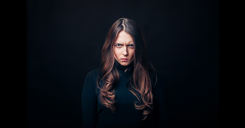 angry looking woman on black background