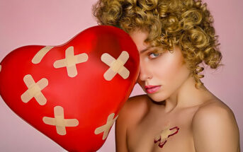 woman holding heart balloon with plasters all over it illustrating the pain and hurt of love