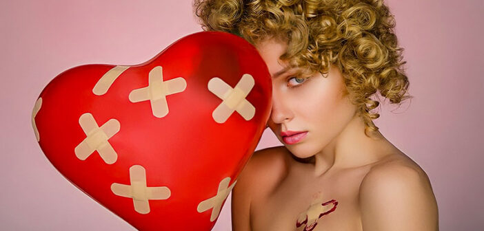 woman holding heart balloon with plasters all over it illustrating the pain and hurt of love