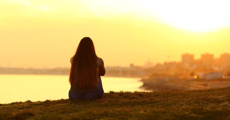 silhouette of a woman looking out across a coastal city - illustrating taking a break from life