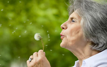 old woman blowing dandelion seeds - illustrating leaving a legacy