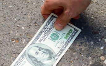 person finding a one hundred dollar bill on the ground - illustrating good luck