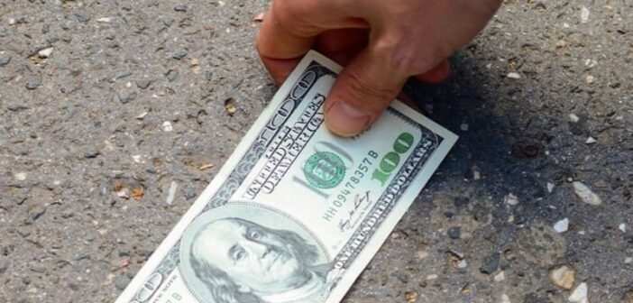 person finding a one hundred dollar bill on the ground - illustrating good luck