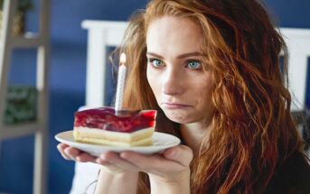 sad woman staring at candle on slice of cake illustrating that she hates her birthday