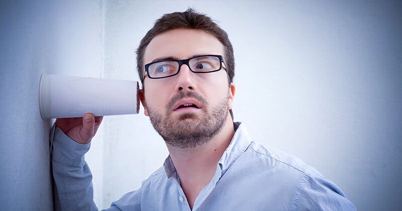 nosy man holding cup against a wall