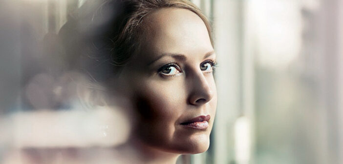 shy woman looking out of window illustrating the need to be more open toward people