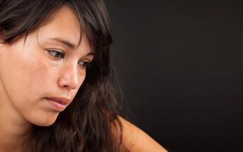 woman looking ashamed against a black background