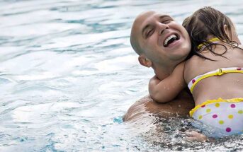 a dad playing with his daughter in a swimming pool