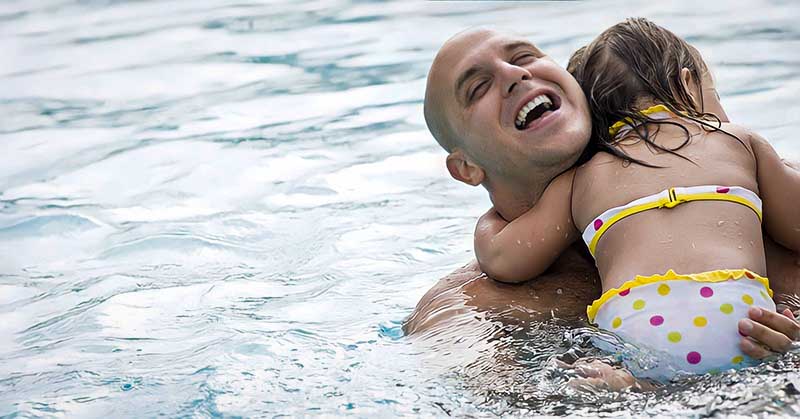 a dad playing with his daughter in a swimming pool
