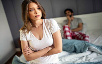 woman with arms crossed standing in front of boyfriend in bed illustrating mismatched sex drives