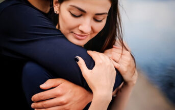 man hugging his girlfriend from behind illustrating her need for constant reassurance in their relationship