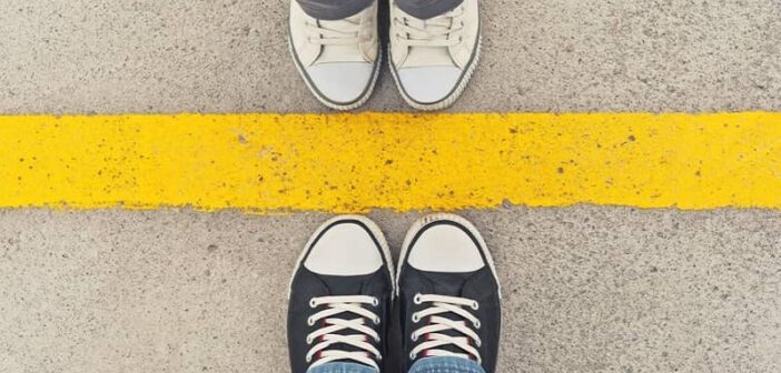 feet of people standing on the opposite side of a yellow line illustrating respecting each other's boundaries