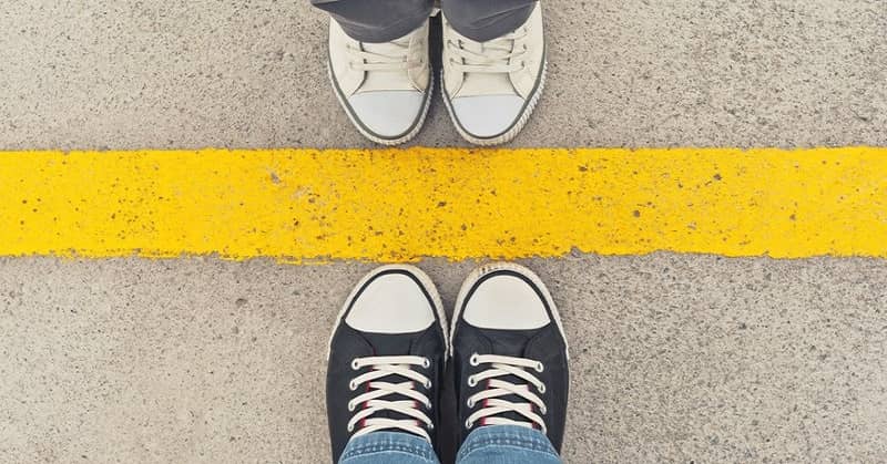 feet of people standing on the opposite side of a yellow line illustrating respecting each other's boundaries