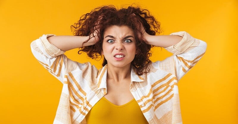 young woman looking annoyed with hands on head and angry expression on her face