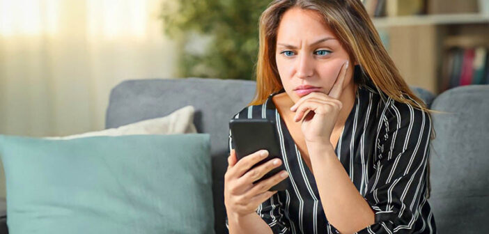 confused young woman staring at her phone wondering why he won't text first