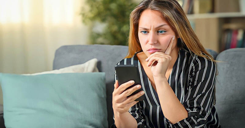 confused young woman staring at her phone wondering why he won't text first