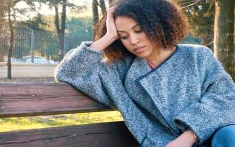 young woman sitting on bench looking like she just doesn't care about anything anymore