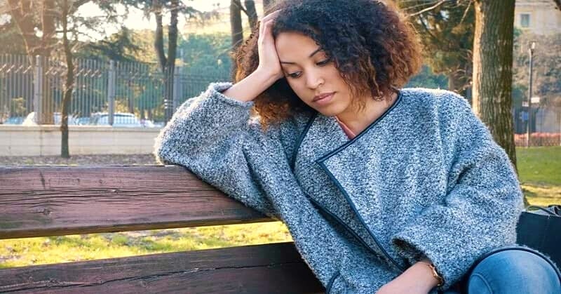 young woman sitting on bench looking like she just doesn't care about anything anymore