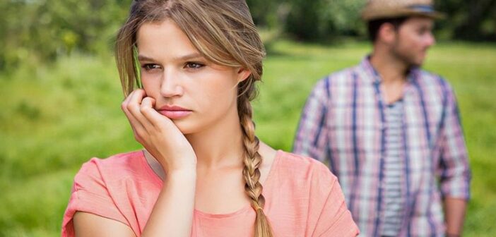 unsure woman with boyfriend in background illustrating signs they might break up