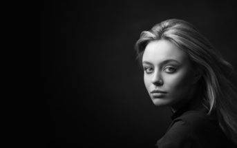 woman with serious face against a black background illustrating being unhappy