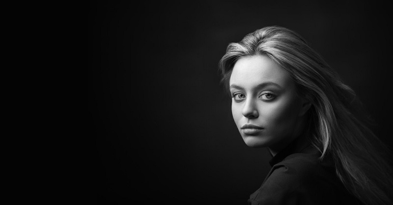 woman with serious face against a black background illustrating being unhappy