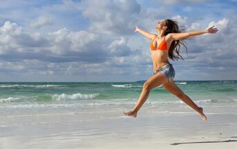 woman jumping up and celebrating on a beach illustrating winning at life