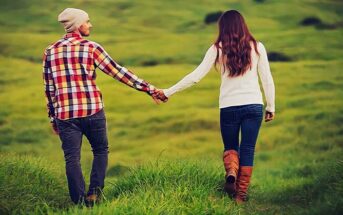 couple holding hands walking through field to illustrate companionship in a relationship