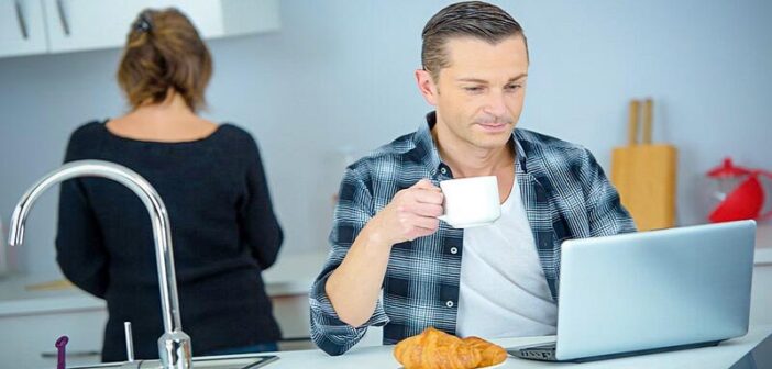 man going through his morning routine drinking coffee and checking his emails on his laptop