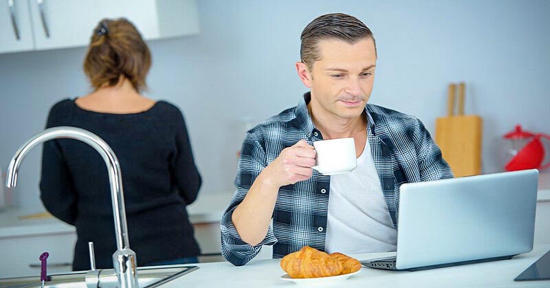 man going through his morning routine drinking coffee and checking his emails on his laptop