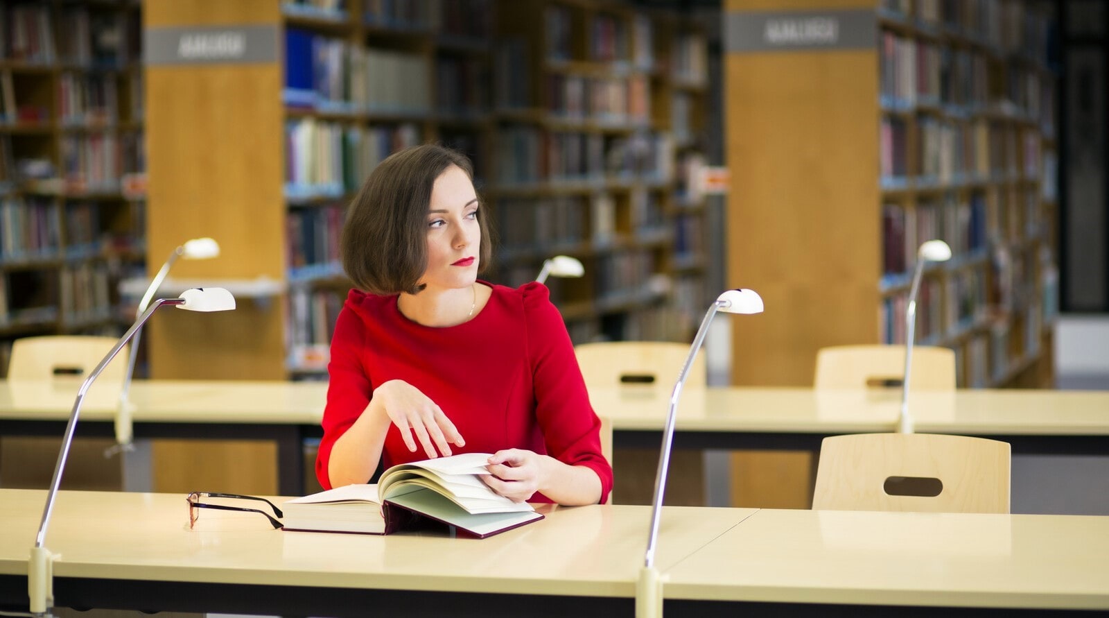 woman reading a large book in a library