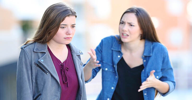 young woman being disrespectful to her friend in the street