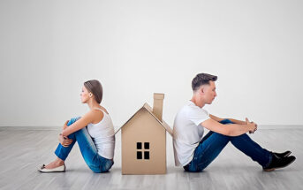 couple sitting facing away from each other with cardboard house between them - illustrating an in-house trial separation