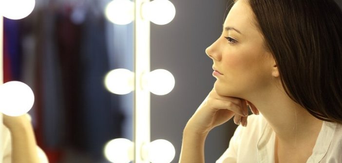 woman looking at her reflection in a mirror to illustrate self-reflection questions