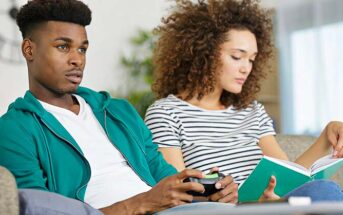 selfish husband playing computer games whilst his wife looks at book