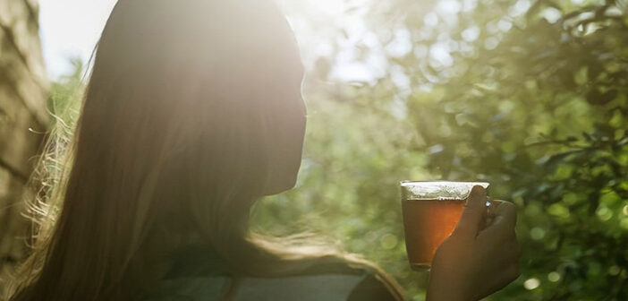 woman drinking tea in her garden to illustrate simple living