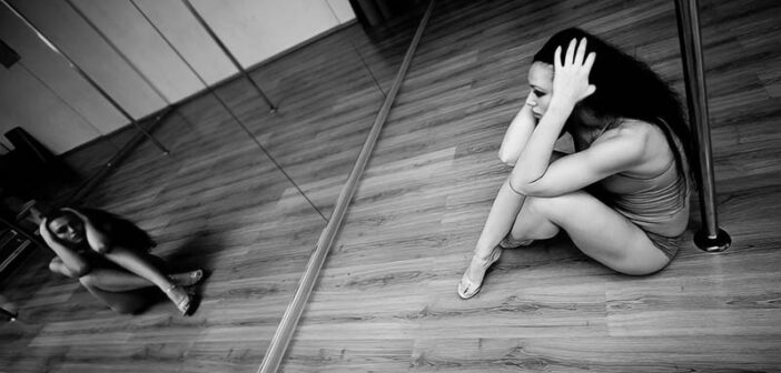 woman in dance studio sitting on floor looking sad - illustrating trying to stay positive in a negative world