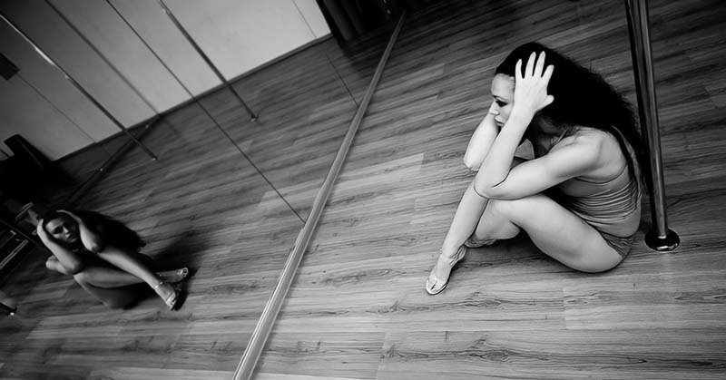 woman in dance studio sitting on floor looking sad - illustrating trying to stay positive in a negative world