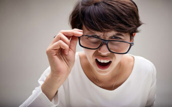 woman with scrunched up face holding her glasses looking very critical of others